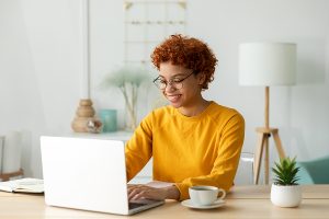 African american girl using laptop at home office looking at screen typing chatting reading writing email. Young woman having virtual meeting online chat video call conference. Work learning from home