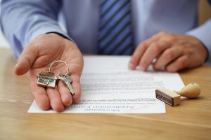 Real estate agent handing over house keys with approved mortgage application form