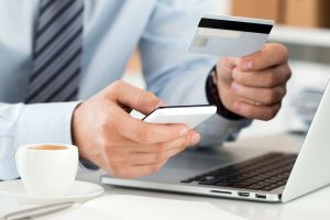 Close up view of businessman hands holding credit card and making online purchase using mobile phone. Shopping consumerism delivery financial security anti-fraud or internet banking concept.