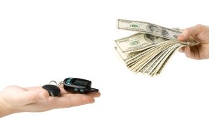 Hand with money and car keys on a white background